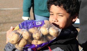 a young boy carries a bag of potatoes from the Mid-South Food Bank