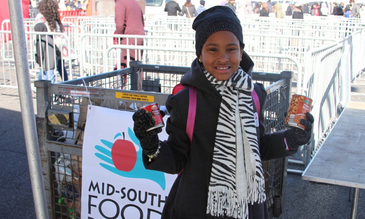 a girl holding up canned goods at the Mid-South Food Bank