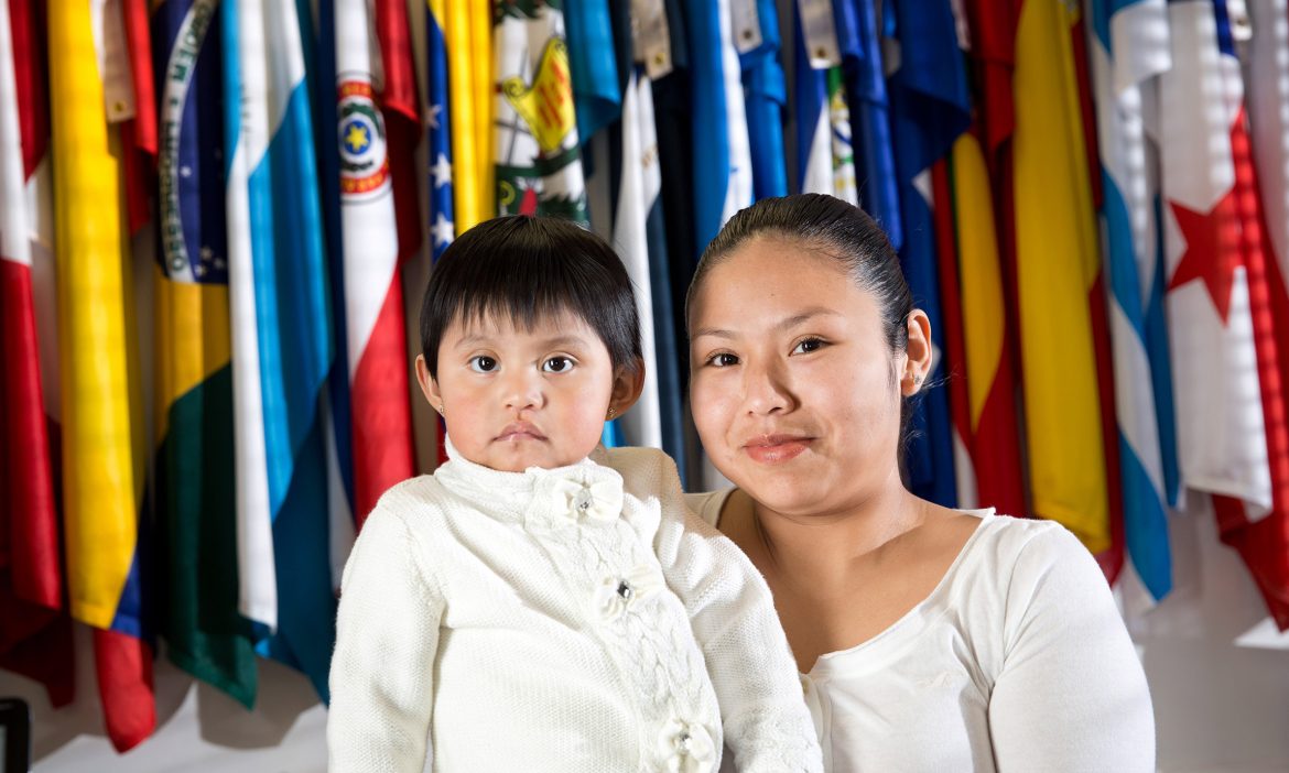 a Latina woman and her child pose in front of international flags at Latino Memphis