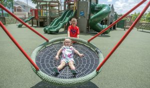 girl on roller table, boy pushing girl on circular swing