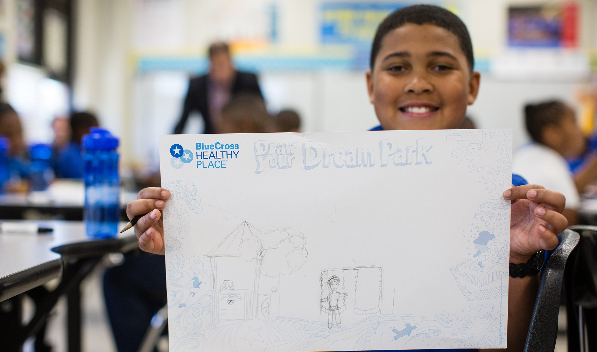 young boy shows his drawing of his dream playground